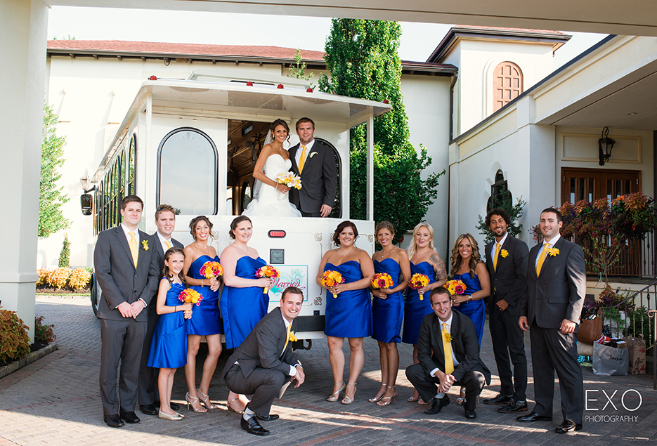 A bridal party poses in front of a white Trolley.